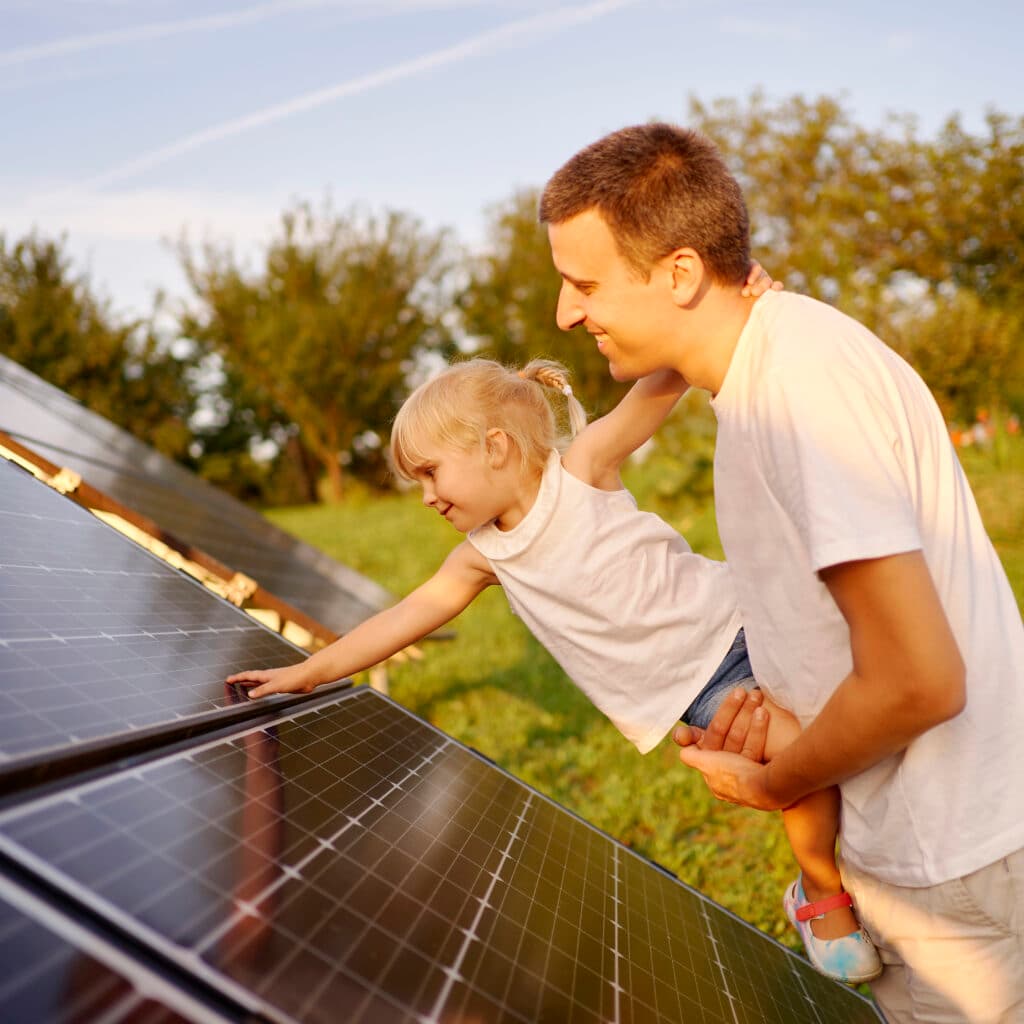 Portrait man holding his young daughter touching solar.